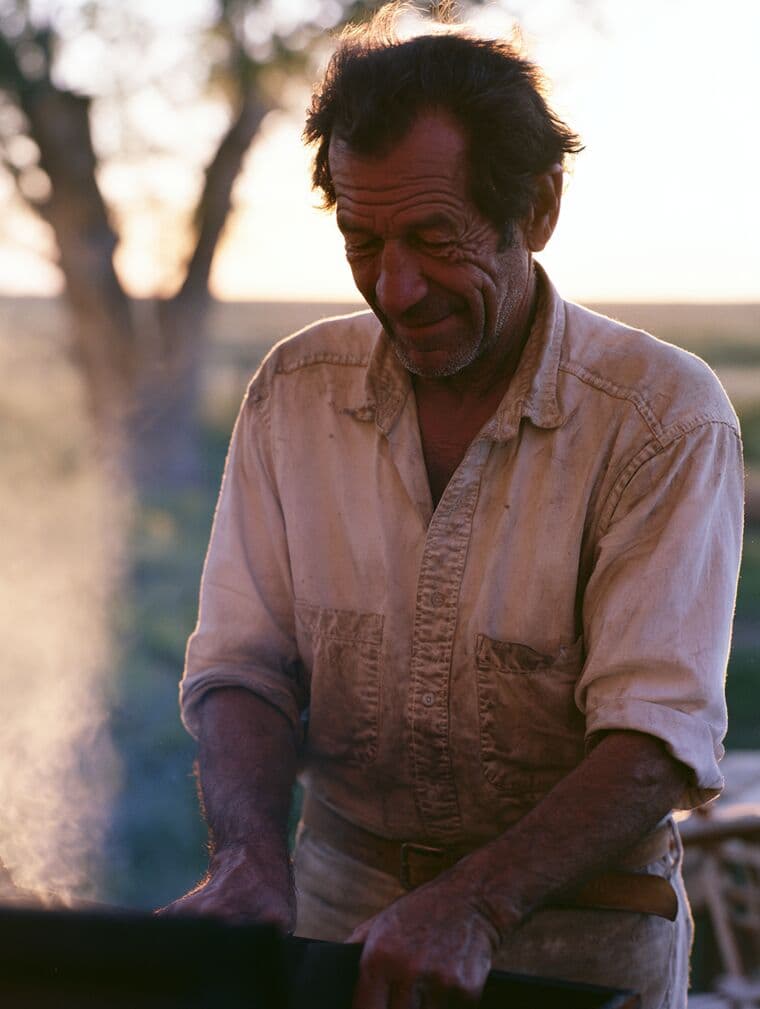 A rancher at a grill in the late afternoon light